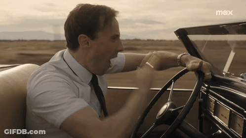 A Man In A White Shirt And Tie Is Driving A Car With The Word Max On The Bottom GIF