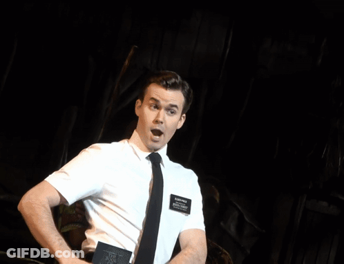 A Man In A White Shirt And Tie Is Laughing While A Woman Stands Behind Him GIF
