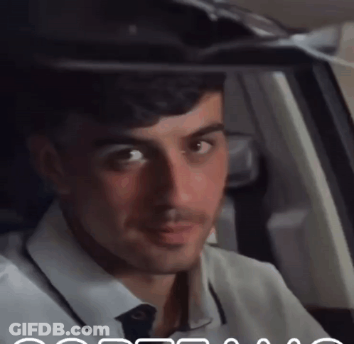 A Man In A White Shirt And Tie Is Looking Out The Window GIF