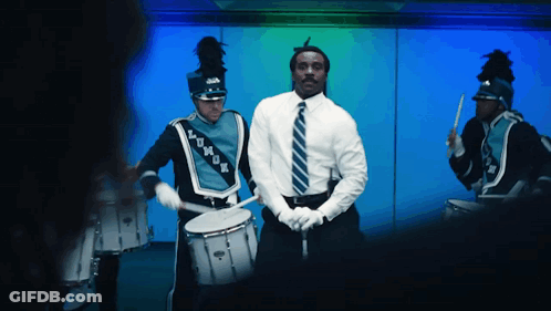 A Man In A White Shirt And Tie Is Playing A Drum GIF