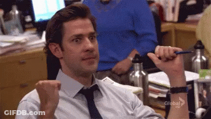 A Man In A White Shirt And Tie Is Sitting At A Desk Holding A Pen In His Hand . GIF