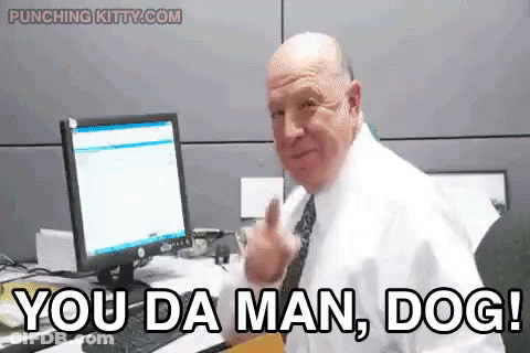 A Man In A White Shirt And Tie Is Sitting At A Desk In Front Of A Computer And Says You Da Man Dog . GIF