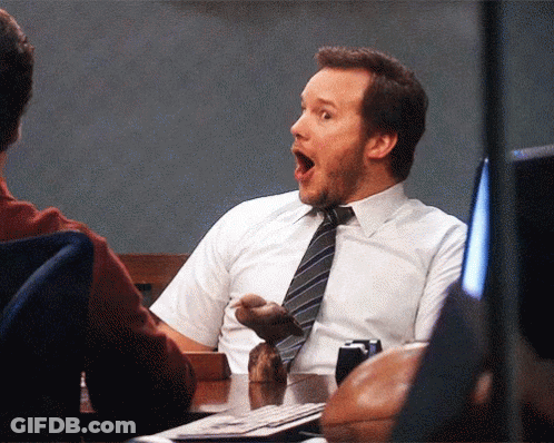 A Man In A White Shirt And Tie Is Sitting At A Desk With His Mouth Open GIF
