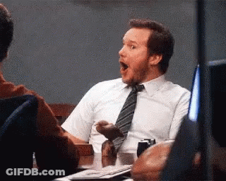 A Man In A White Shirt And Tie Is Sitting At A Table With His Mouth Wide Open . GIF