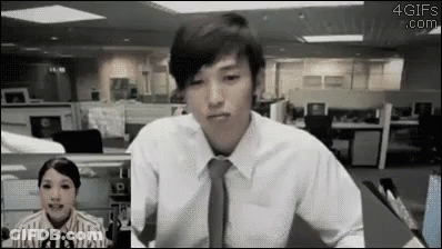A Man In A White Shirt And Tie Is Sitting In Front Of A Woman In An Office Cubicle . GIF