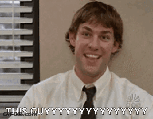 A Man In A White Shirt And Tie Is Smiling While Sitting In Front Of A Window In An Office . GIF
