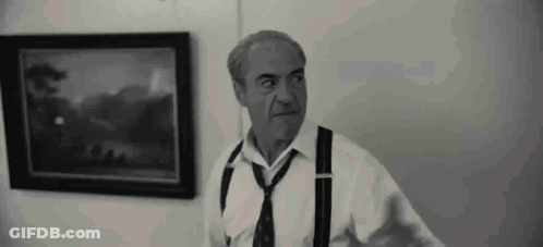A Man In A White Shirt And Tie Is Standing In Front Of A Painting . GIF