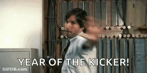 A Man In A White Shirt And Tie Is Standing In Front Of A Wall And Says `` Year Of The Kicker '' . GIF