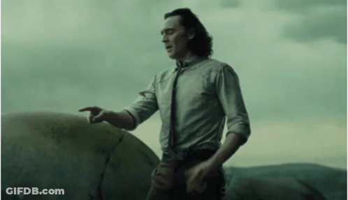 A Man In A White Shirt And Tie Is Standing Next To A Large Rock And Pointing At It . GIF