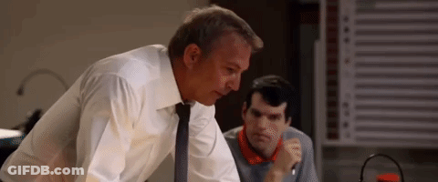 A Man In A White Shirt And Tie Is Standing Next To Another Man In A Room . GIF