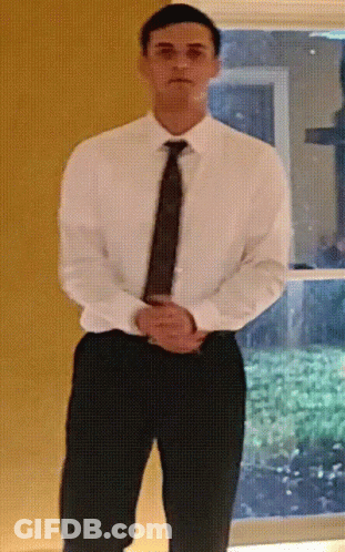 A Man In A White Shirt And Tie Is Standing With His Hands On His Hips GIF