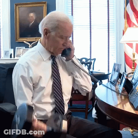 A Man In A White Shirt And Tie Is Talking On A Cell Phone GIF
