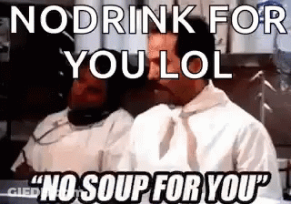 A Man In A White Shirt And Tie Is Talking On A Phone In A Kitchen . GIF
