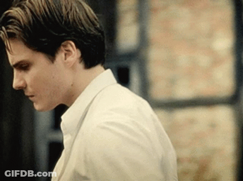 A Man In A White Shirt And Tie Looks Down At Something GIF
