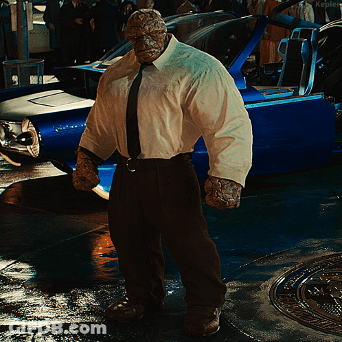 A Man In A White Shirt And Tie Stands In Front Of A Blue Car That Says Kepler GIF