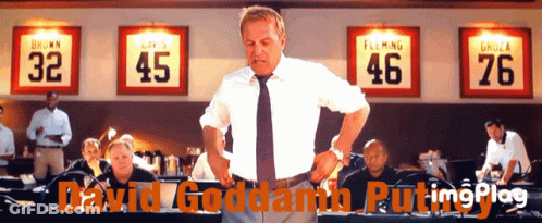 A Man In A White Shirt And Tie Stands In Front Of A Row Of Jerseys With The Numbers 32 45 46 And 76 GIF