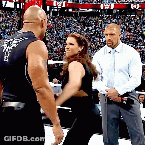 A Man In A White Shirt And Tie Stands Next To A Woman In A Black Tank Top With A Bull On It GIF