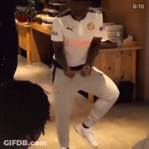 A Man In A White Shirt And White Pants Is Dancing In A Kitchen . GIF