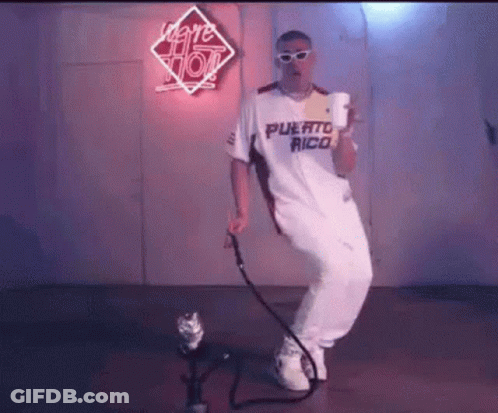 A Man In A White Shirt And White Pants Is Dancing In Front Of A Microphone . GIF