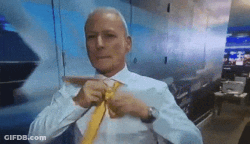 A Man In A White Shirt And Yellow Tie Is Tying His Tie . GIF