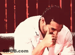 A Man In A White Shirt Covering His Mouth With His Hands GIF