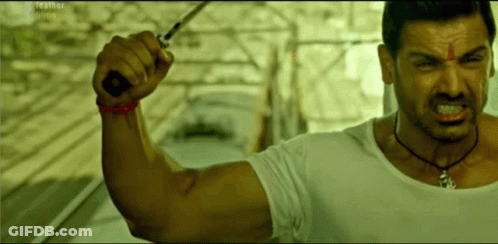 A Man In A White Shirt Holds A Knife In His Hand GIF