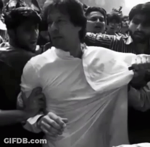 A Man In A White Shirt Is Being Pulled By A Crowd Of People GIF