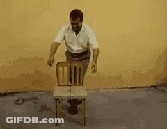 A Man In A White Shirt Is Carrying A Black Box On His Back GIF