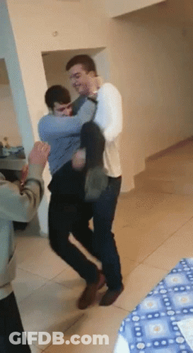 A Man In A White Shirt Is Carrying Another Man In His Arms GIF