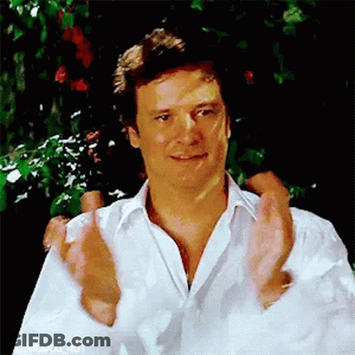 A Man In A White Shirt Is Clapping His Hands In Front Of A Tree . GIF