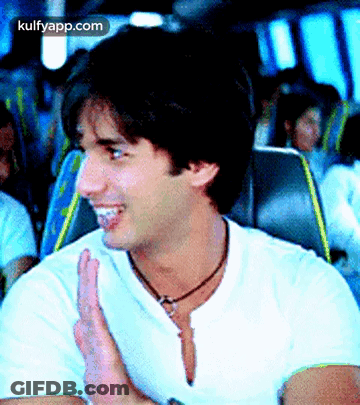 A Man In A White Shirt Is Clapping His Hands While Sitting On A Bus .. GIF