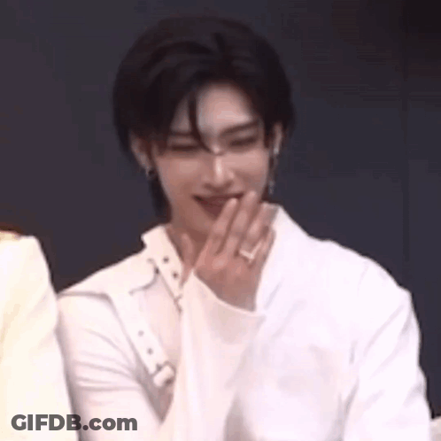 A Man In A White Shirt Is Covering His Mouth With His Hand While Sitting Next To Another Man . GIF