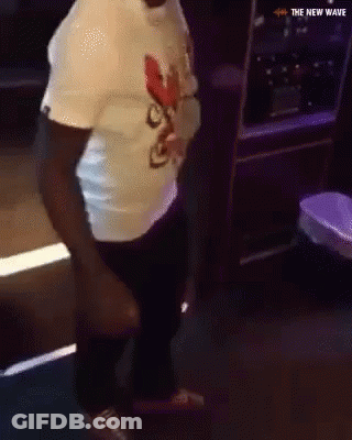 A Man In A White Shirt Is Dancing In A Dark Room With The New Wave Written On The Bottom GIF
