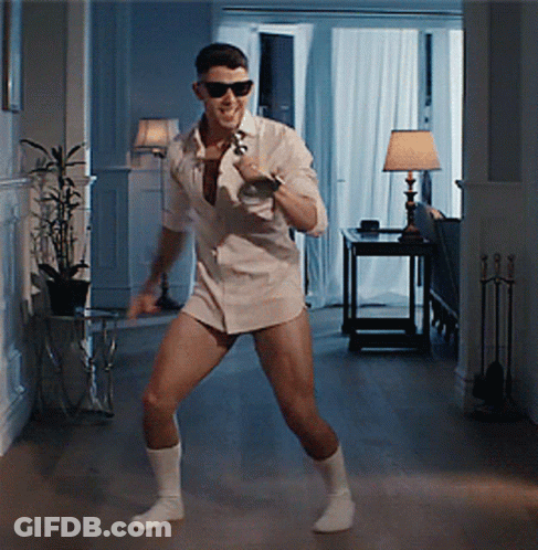 A Man In A White Shirt Is Dancing In A Hallway GIF