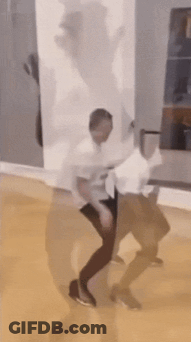 A Man In A White Shirt Is Dancing In A Room With His Shadow Behind Him GIF