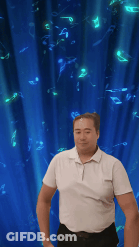 A Man In A White Shirt Is Dancing In Front Of A Blue Curtain With Music Notes On It GIF