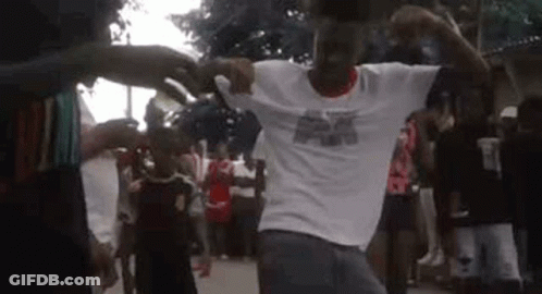 A Man In A White Shirt Is Dancing In Front Of A Crowd . GIF