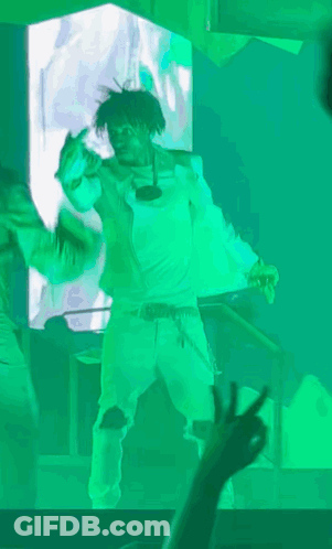 A Man In A White Shirt Is Dancing In Front Of A Green Screen GIF