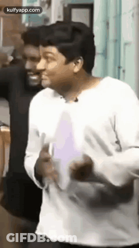 A Man In A White Shirt Is Dancing In Front Of A Man In A Black Shirt . GIF