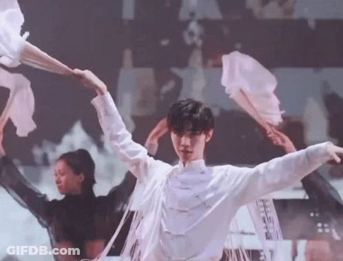 A Man In A White Shirt Is Dancing On A Stage With A Group Of Dancers . GIF