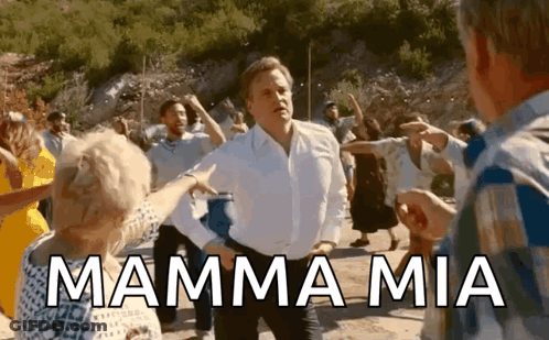 A Man In A White Shirt Is Dancing With A Group Of People And The Words Mamma Mia Are Written Above Him . GIF