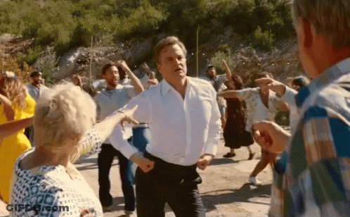 A Man In A White Shirt Is Dancing With A Group Of People In A Crowd . GIF