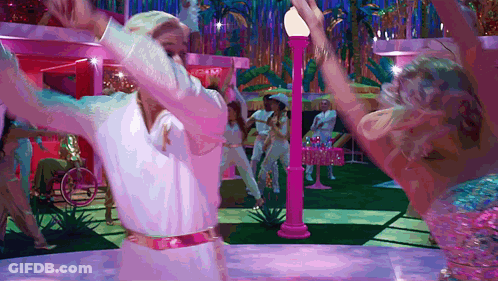 A Man In A White Shirt Is Dancing With A Woman In A Pink Outfit GIF