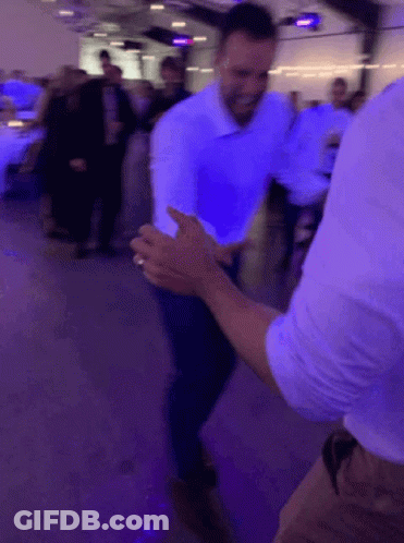 A Man In A White Shirt Is Dancing With Another Man In A Blue Shirt . GIF