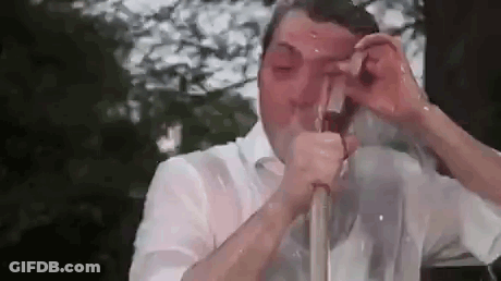 A Man In A White Shirt Is Drinking From A Hose . GIF