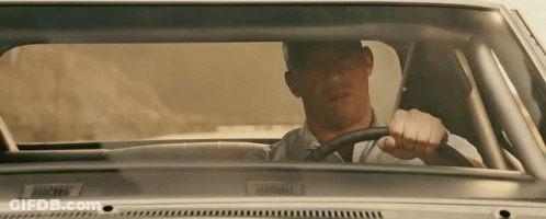 A Man In A White Shirt Is Driving A Car With A License Plate That Says ' Bmw ' GIF