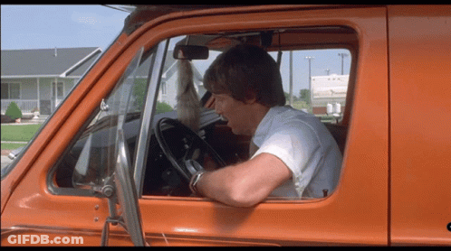 A Man In A White Shirt Is Driving An Orange Truck GIF