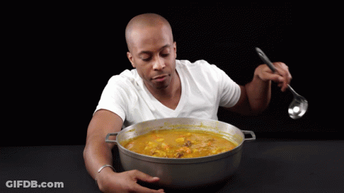 A Man In A White Shirt Is Eating A Large Pot Of Soup With A Ladle GIF