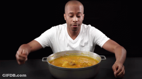 A Man In A White Shirt Is Eating From A Large Pot GIF