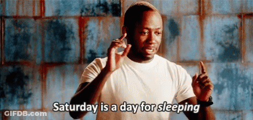 A Man In A White Shirt Is Giving A Thumbs Up And Saying `` Saturday Is A Day For Sleeping '' . GIF